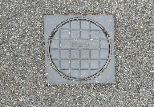 grey plastic water meter cover with a round lib labelled water. 