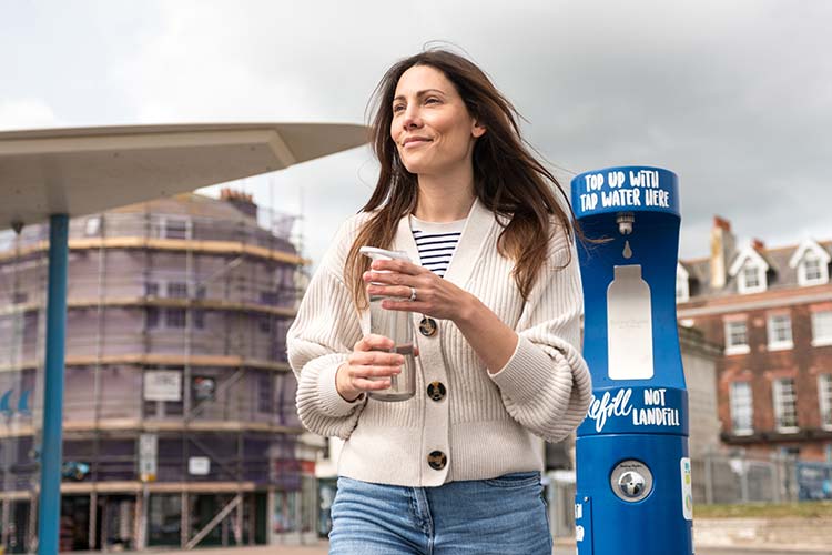 A woman standing next to a water refill point