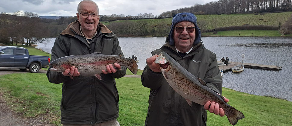 Two anglers holding fishes
